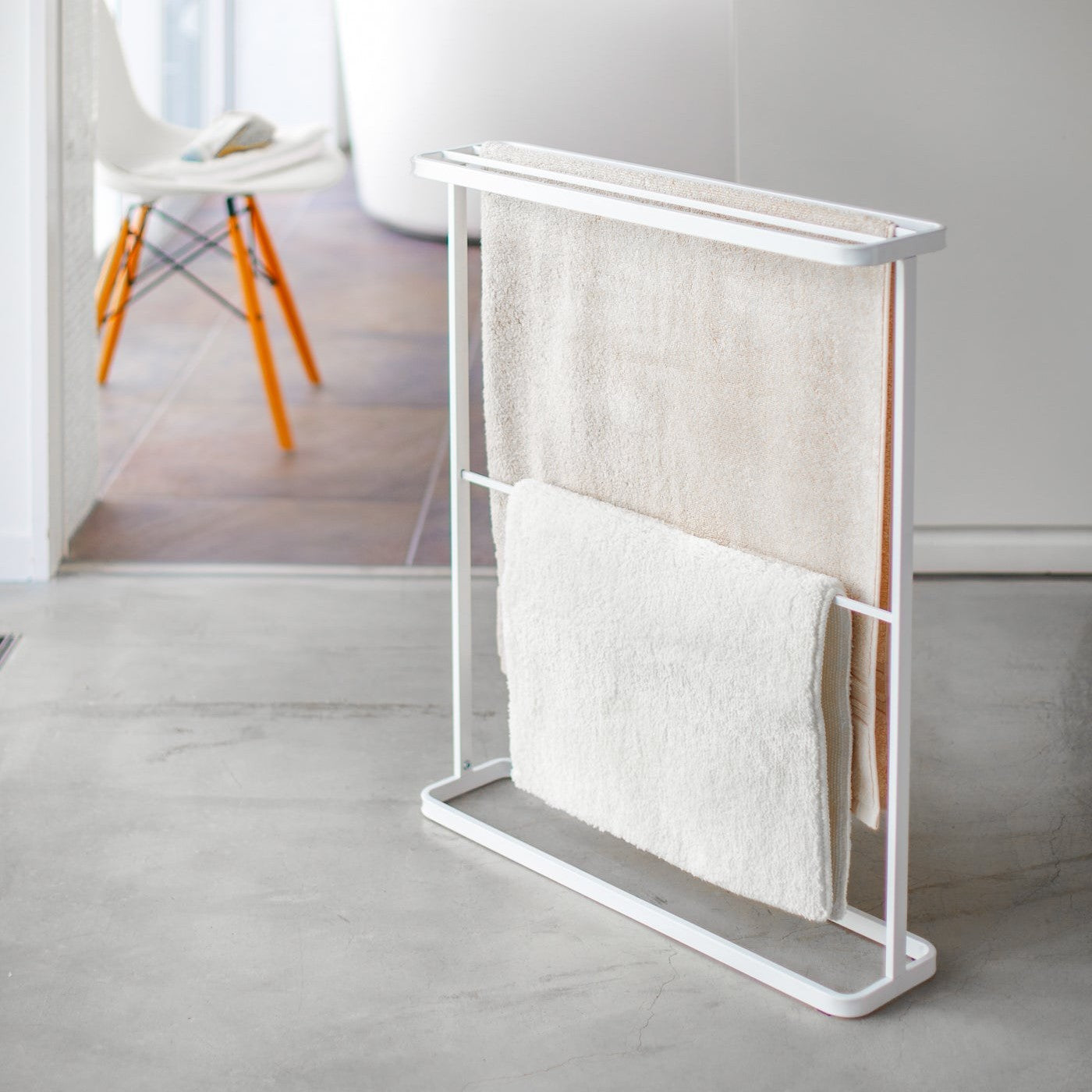 White Bath Towel Hanger holding mat and towel by Yamazaki Home.