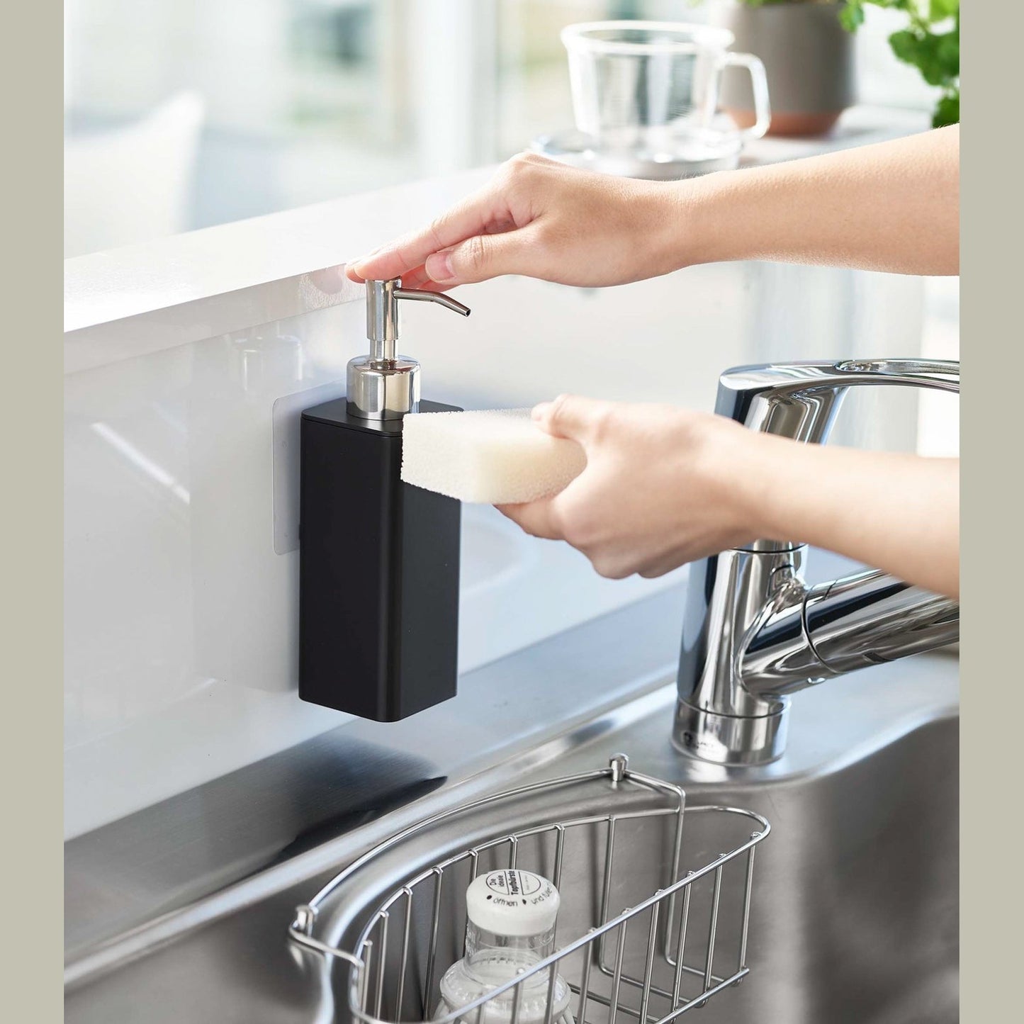 Dispensing soap from black Yamazaki Home square soap dispenser onto dish sponge