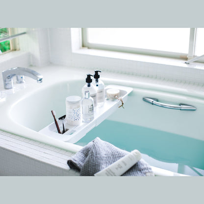 White Expandable Bathtub Caddy holding beauty cleaning products in bathtub by Yamazaki Home.