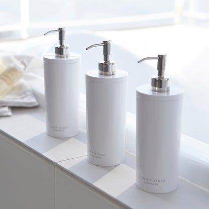Yamazaki Home white Shampoo, Conditioner, and Body Soap dispensers in bathroom.