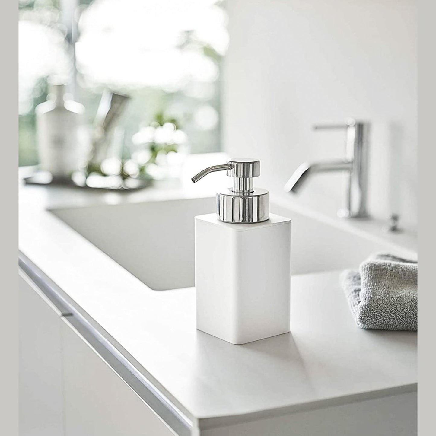 White Foaming Soap Dispenser on bathroom sink countertop by Yamazaki Home.