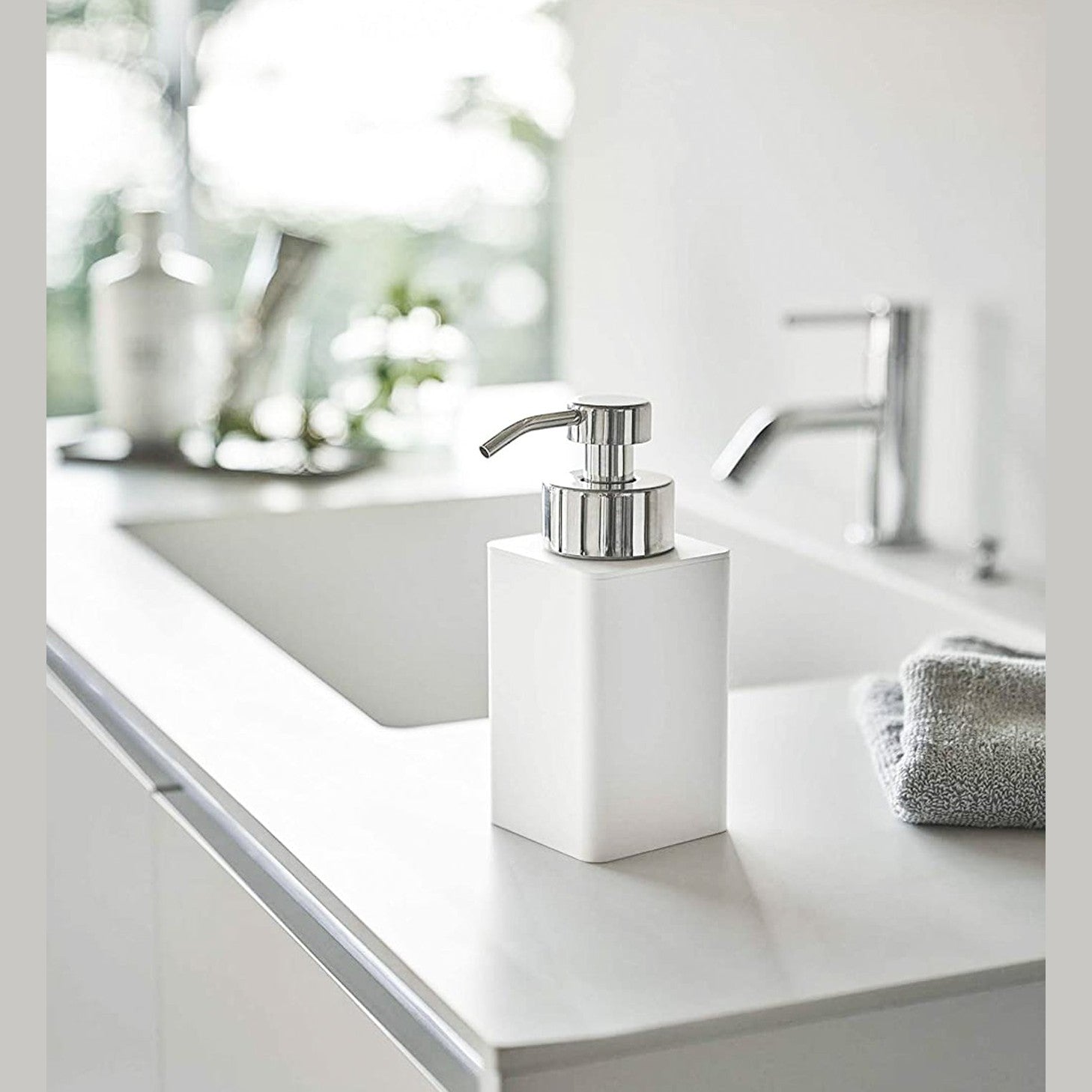 White Foaming Soap Dispenser on bathroom sink countertop by Yamazaki Home.
