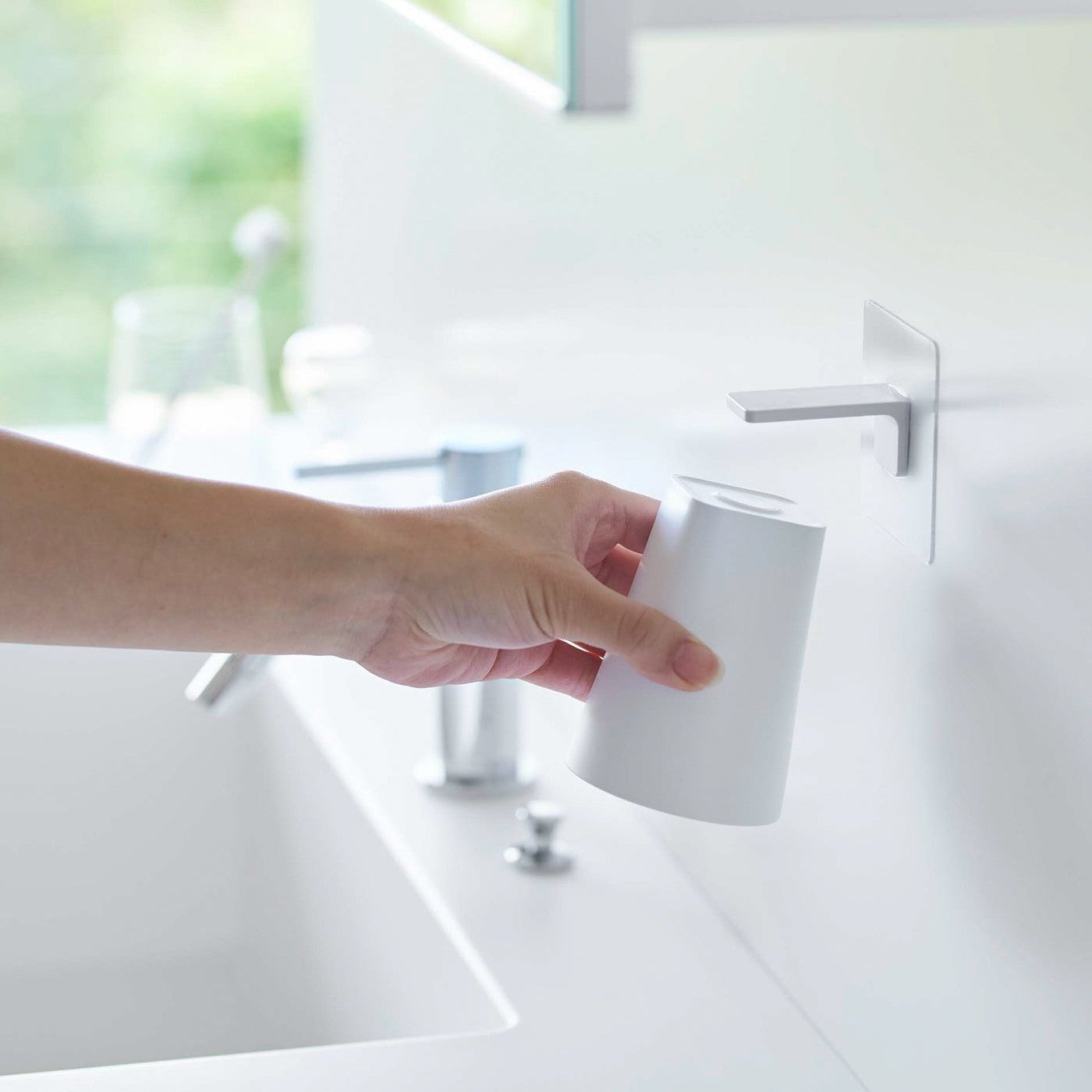 Removing white Yamazaki Home traceless adhesive magnetic cup installed next to sink