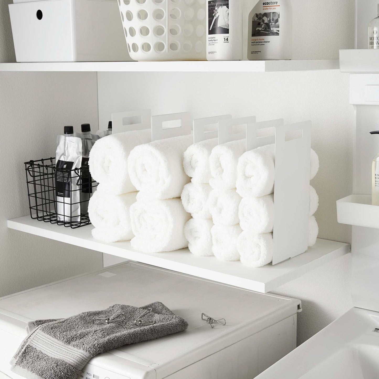 White Towel Storage Organizer holding towels in laundry room by Yamazaki Home.