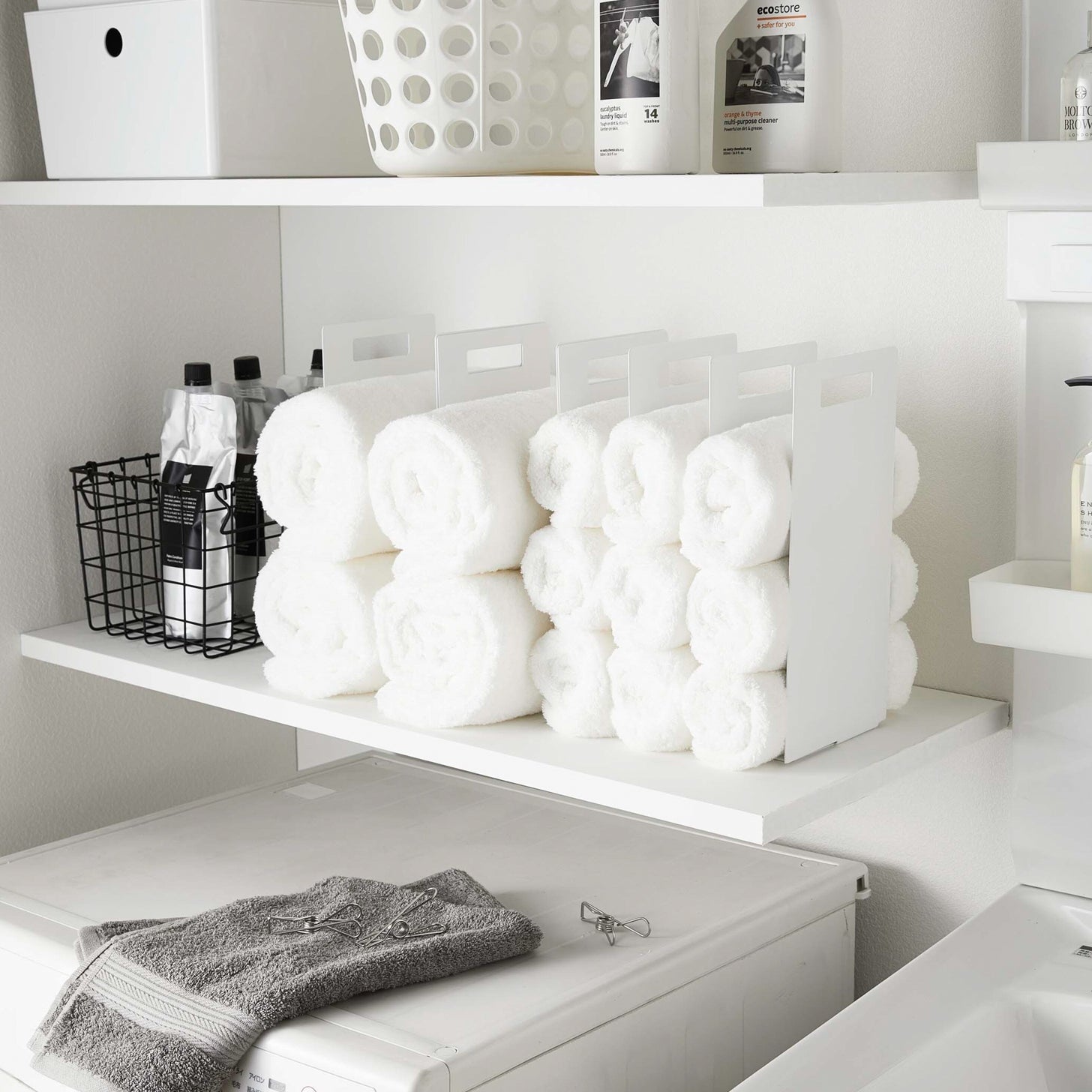 White Towel Storage Organizer holding towels in laundry room by Yamazaki Home.
