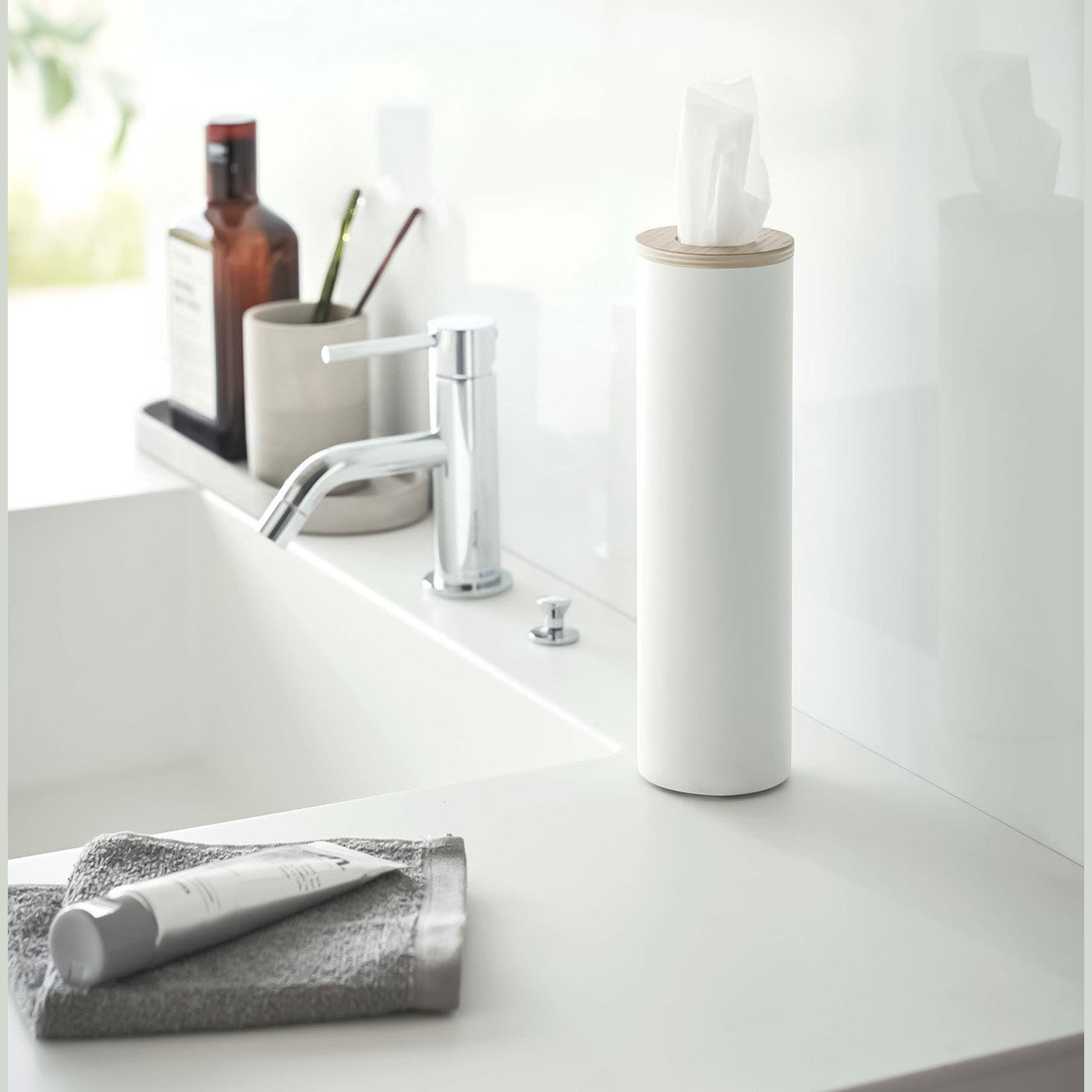 Small white Yamazaki Home Round Tissue Case on a sink counter