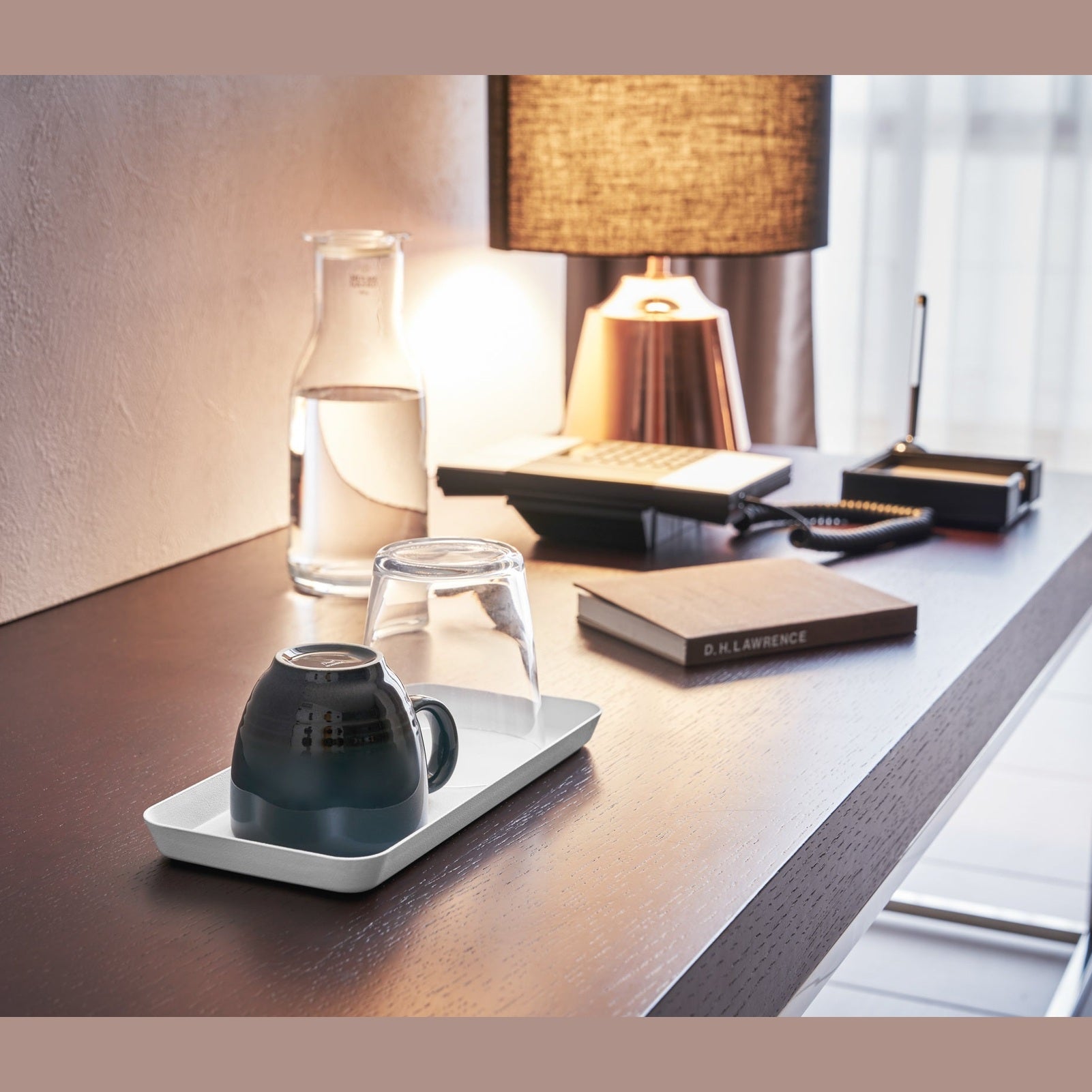 White Accessory Tray holding mug and glass on desk by Yamazaki Home.