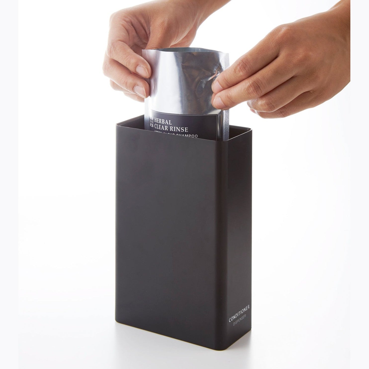 Black Conditioner Dispenser filled with soap on white background by Yamazaki Home.