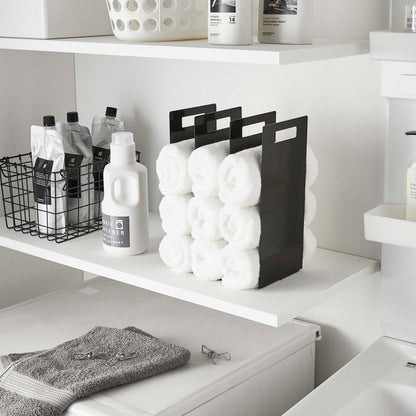 Black Towel Storage Organizer holding towels in laundry room by Yamazaki Home.