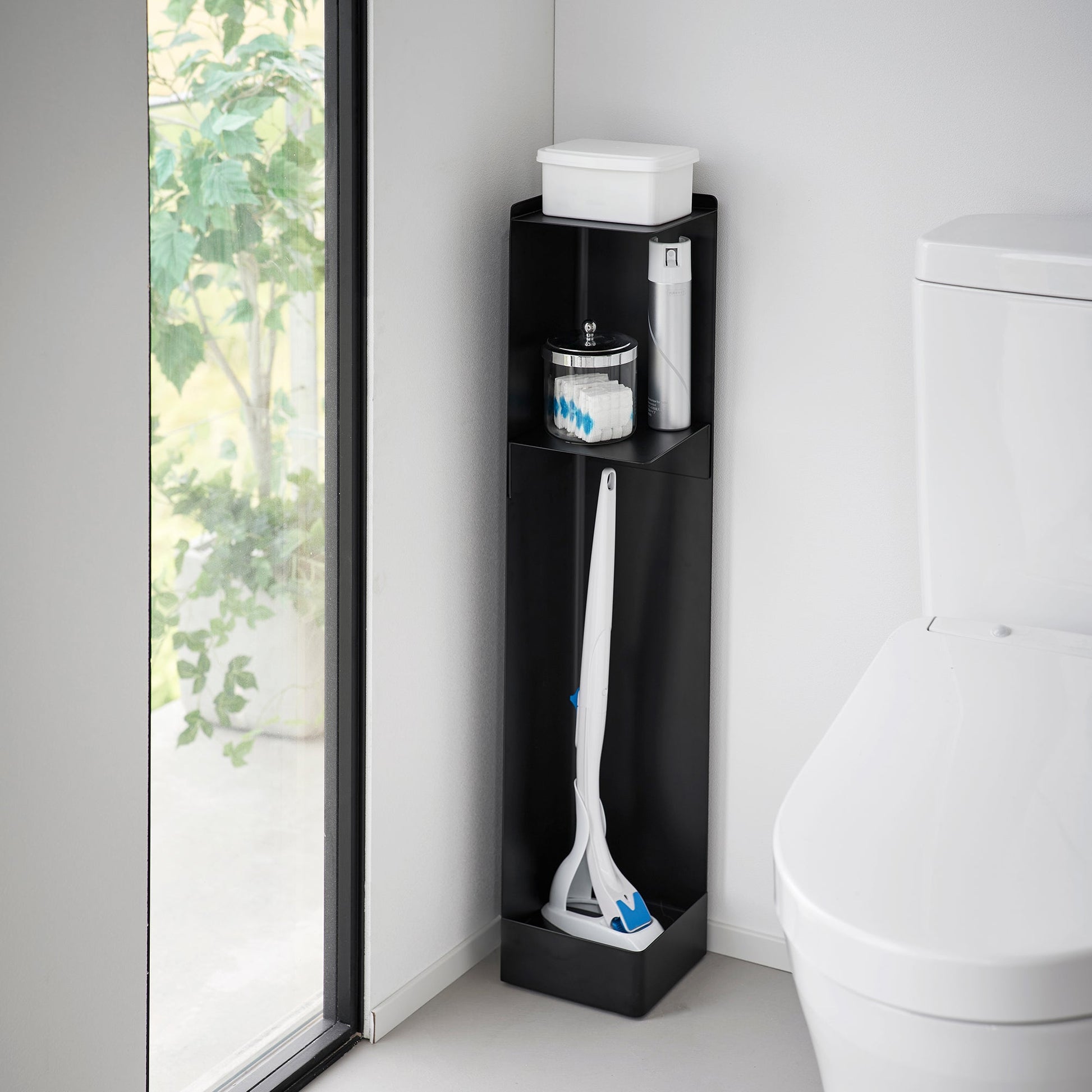 Black Yamazaki Home Rolling Bathroom Organizer next to a toilet storing a toilet brush, cleaning spray and wet wipes