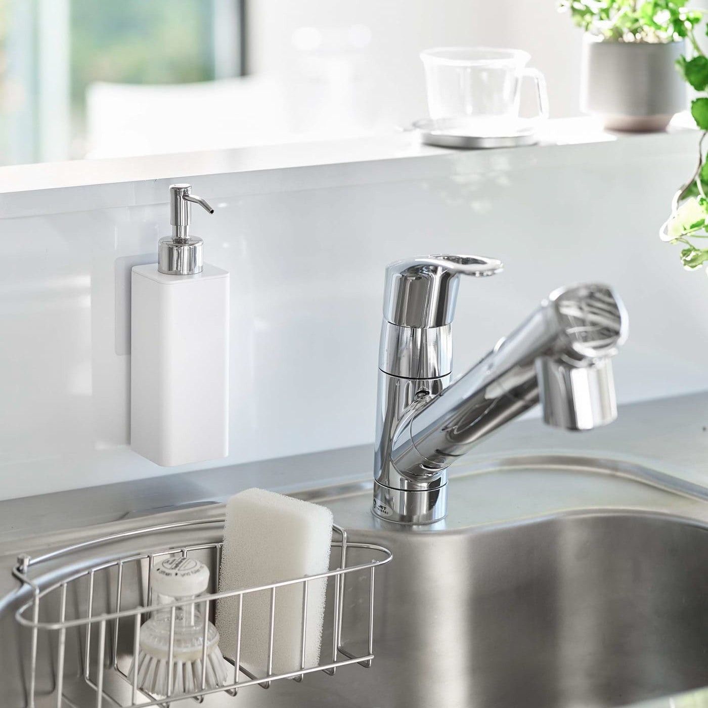 White Yamazaki Home square soap dispenser hooked in front of kitchen sink