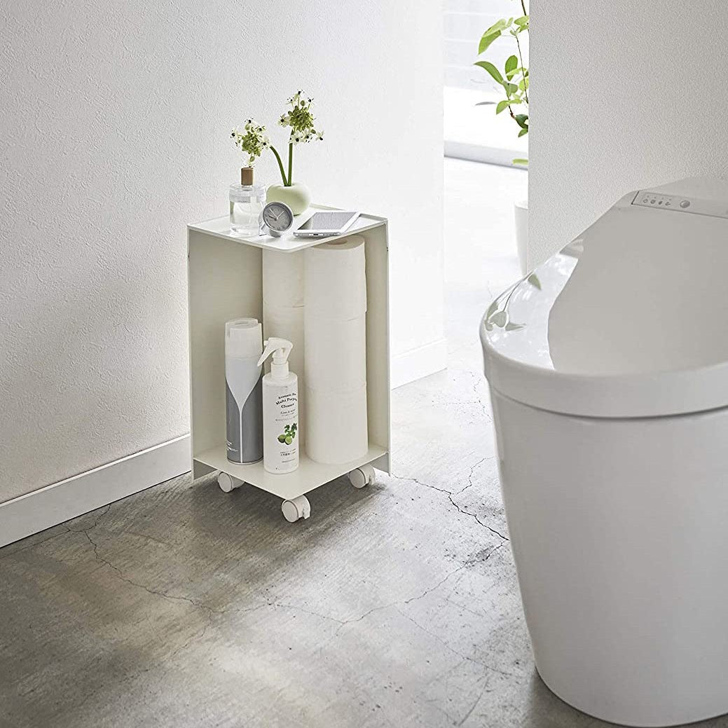 White Rolling Bathroom Organizer holding toilet paper and supplies in bathroom by Yamazaki Home.