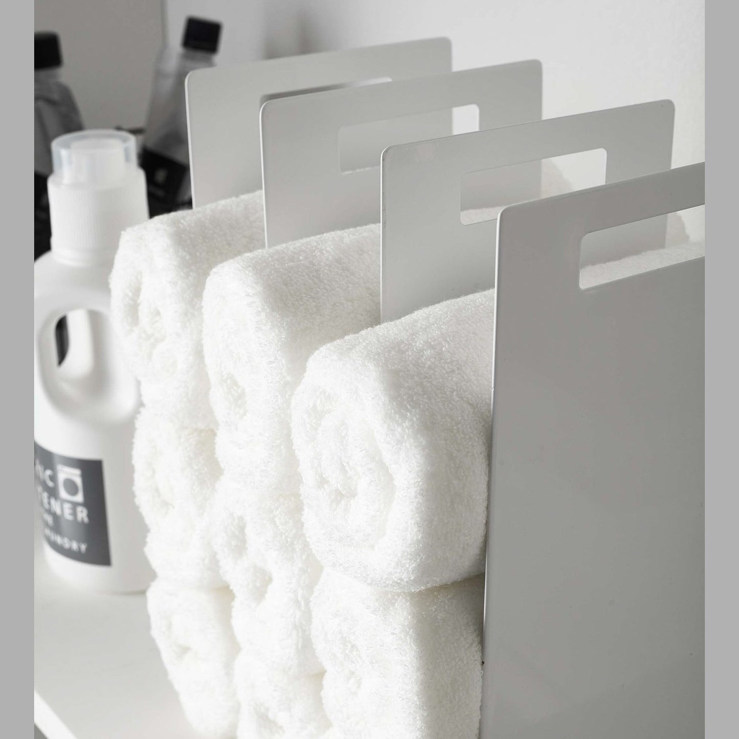 Close up side view of white Towel Storage Organizer holding towels by Yamazaki Home.