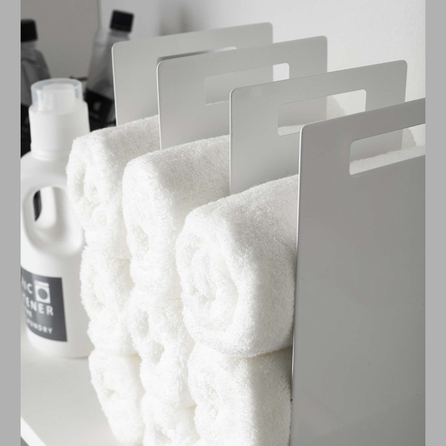 Close up side view of white Towel Storage Organizer holding towels by Yamazaki Home.