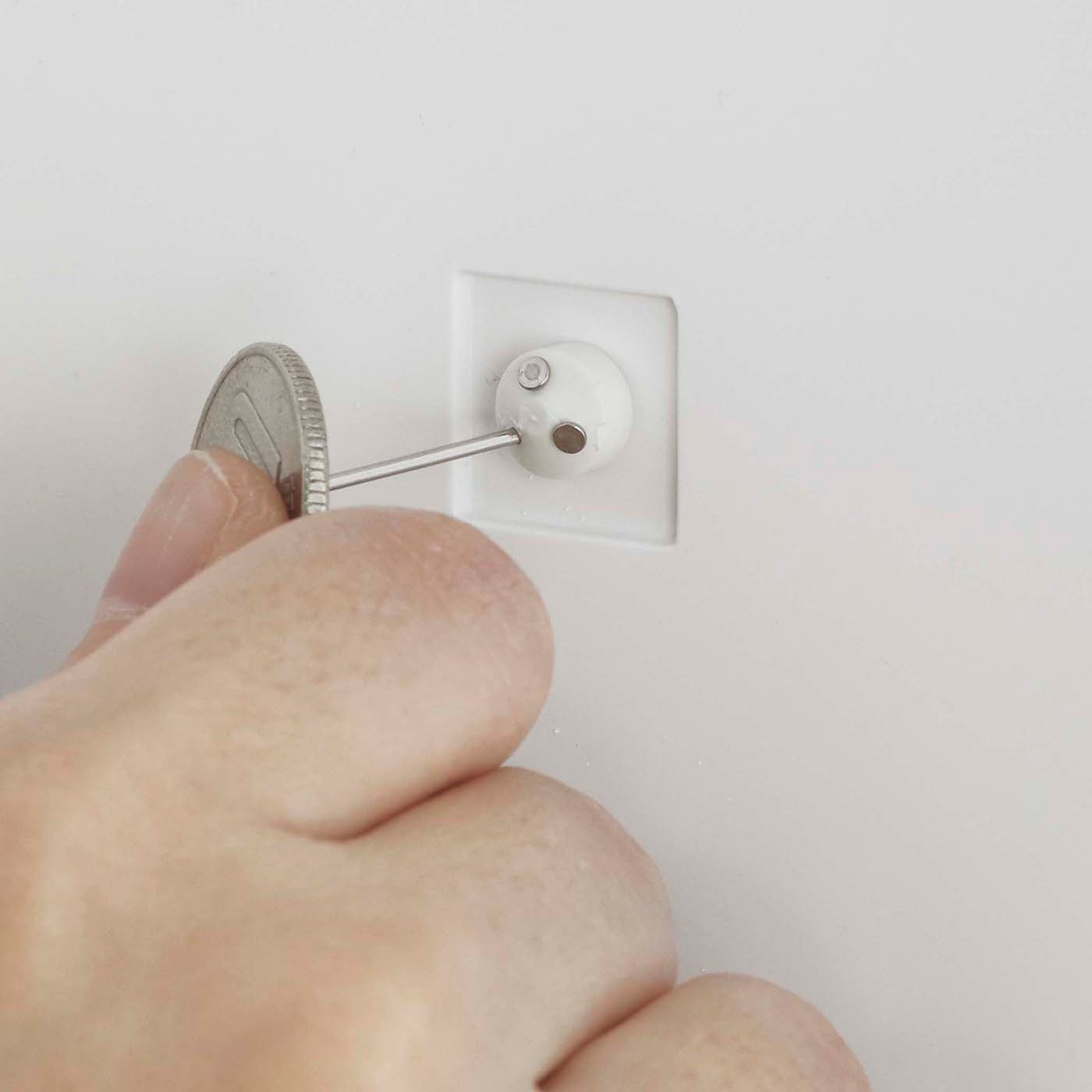 Close up view of person attatching item to white Wall-Mount Storage by Yamazaki Home.