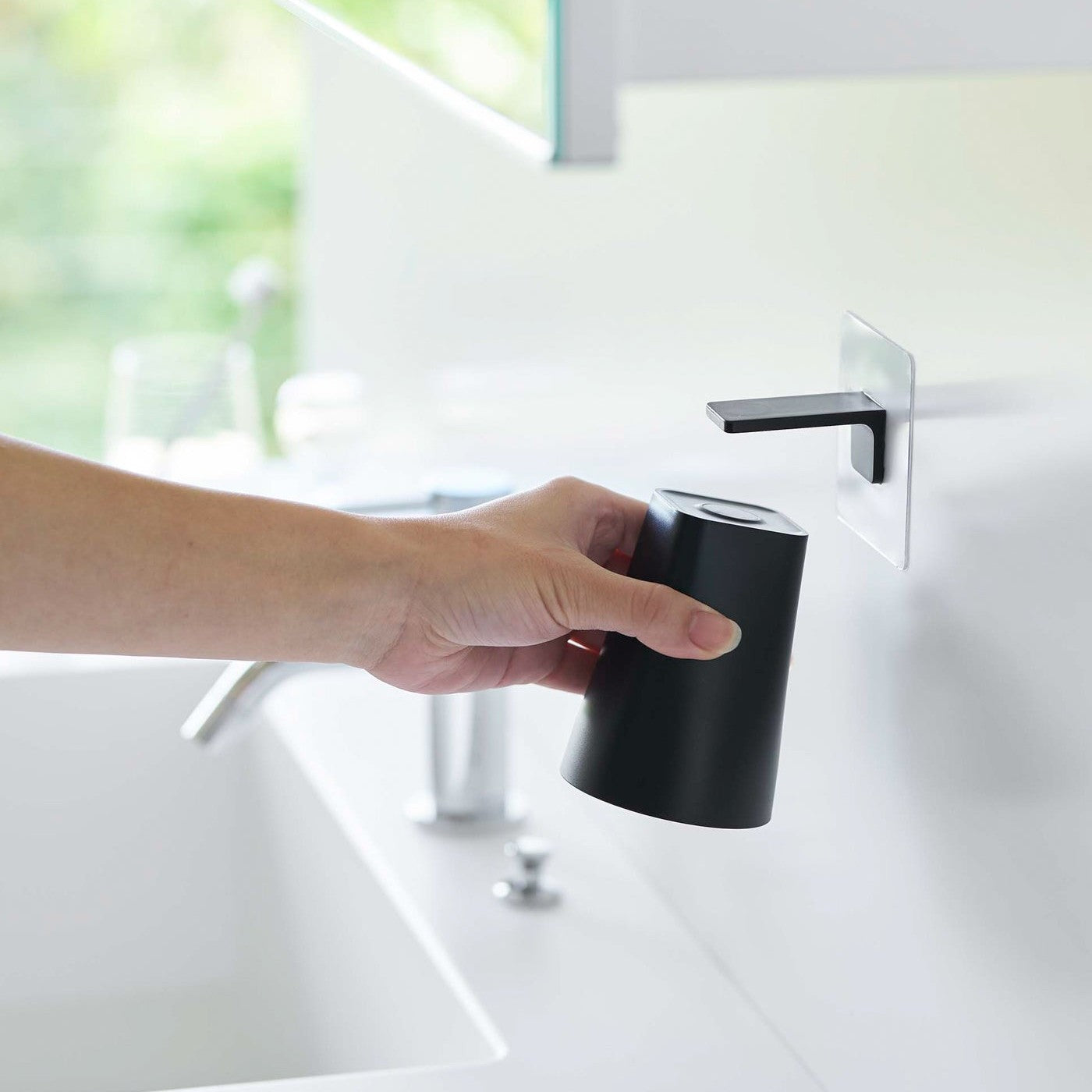 Removing white Yamazaki Home traceless adhesive magnetic cup installed next to sink