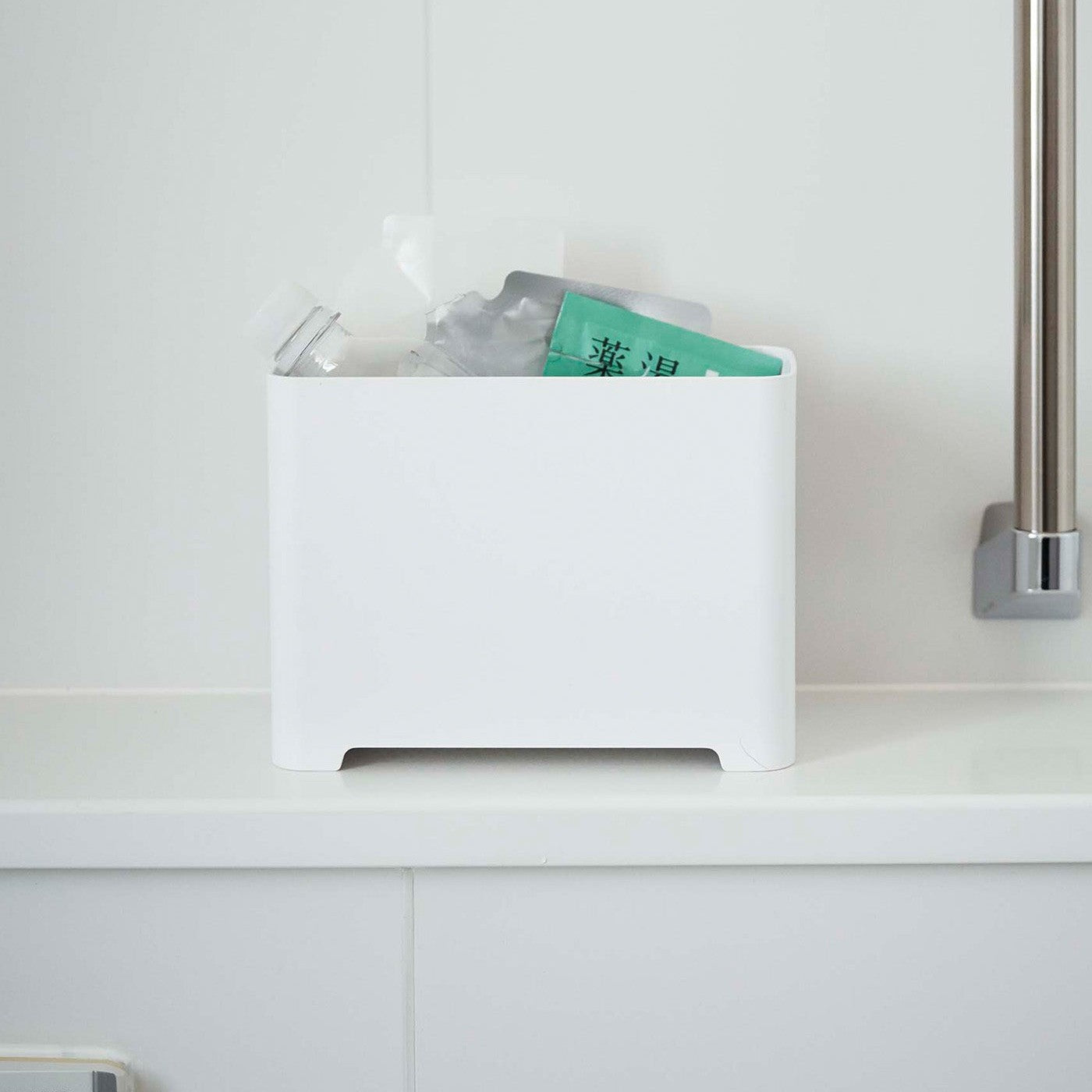 Frontal view of white Yamazaki Self-Draining Bathroom Organizer filled with bath supplies