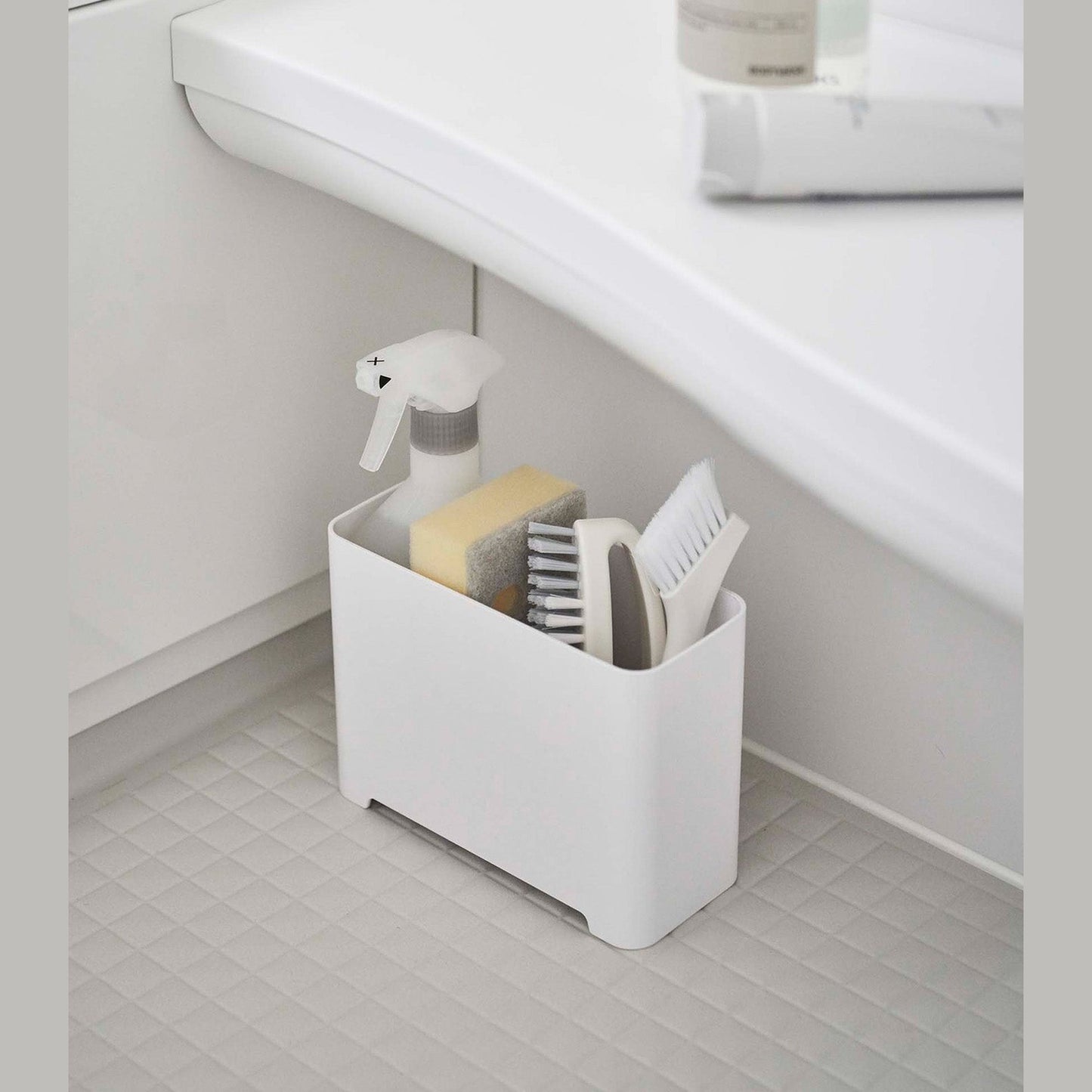 White Yamazaki Self-Draining Bathroom Organizer filled with cleaning supplies
