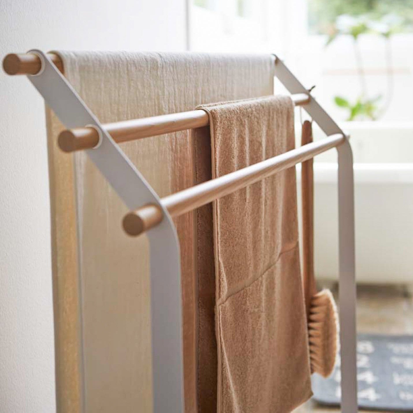 Close up side view of Bath Towel Rack holding towels in bathroom by Yamazaki Home.