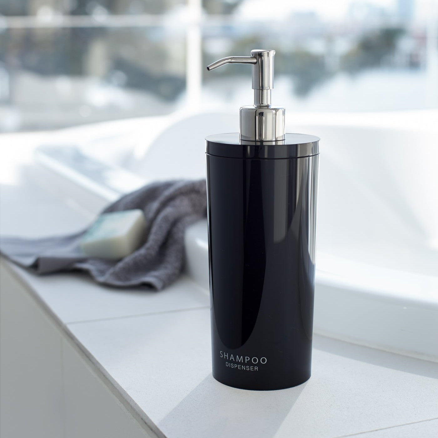 Front view of black Shampoo Dispenser on bathtub edge by Yamazaki Home.