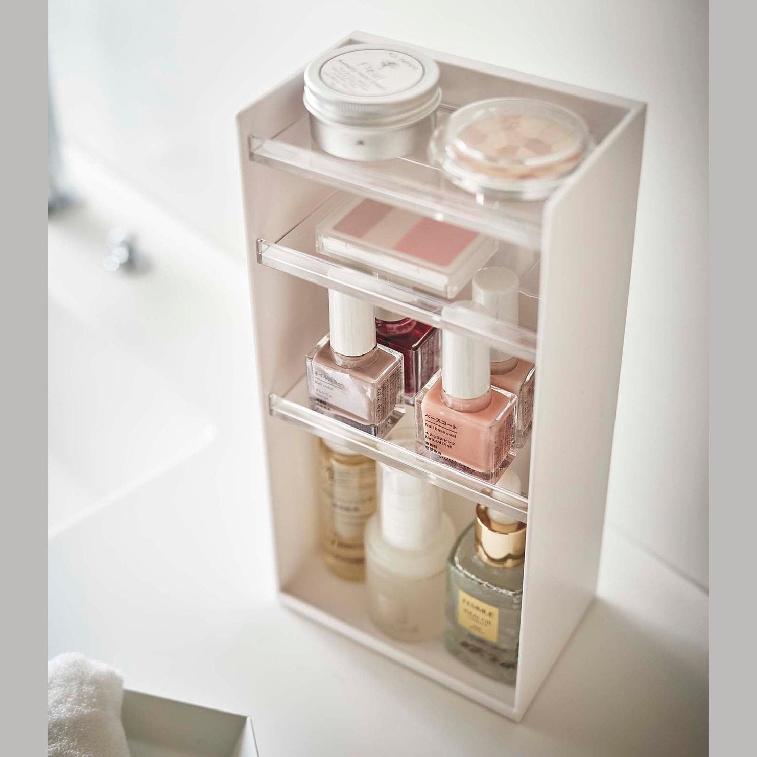 White Cosmetics Storage Tower by Yamazaki Home holding nail polish and other cosmetic items.