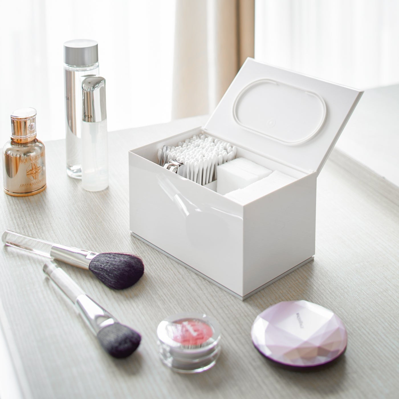 Open white Skincare Organizer holding cotton tips, cotton pads and nail clippers by Yamazaki Home.