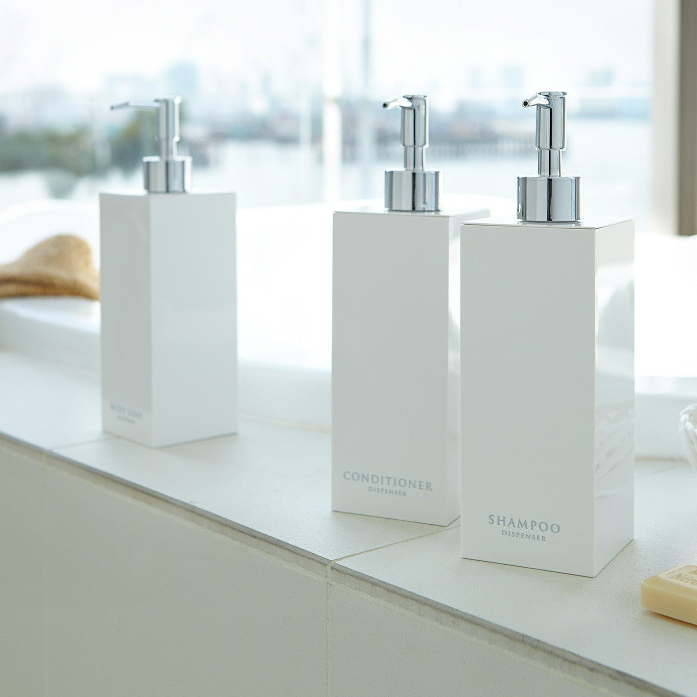 White Yamazaki Home soap dispenser in three styles by bathtub