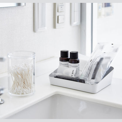 Angeled front view of medium white Accessory Tray holding beauty items on bathroom sink counter by Yamazaki Home.
