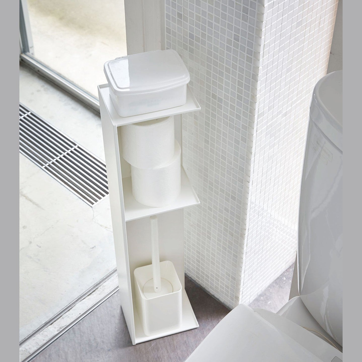 Yamazaki Home white Toilet Organizer holding wet wipe case, toilet paper, and toilet brush in bathroom.