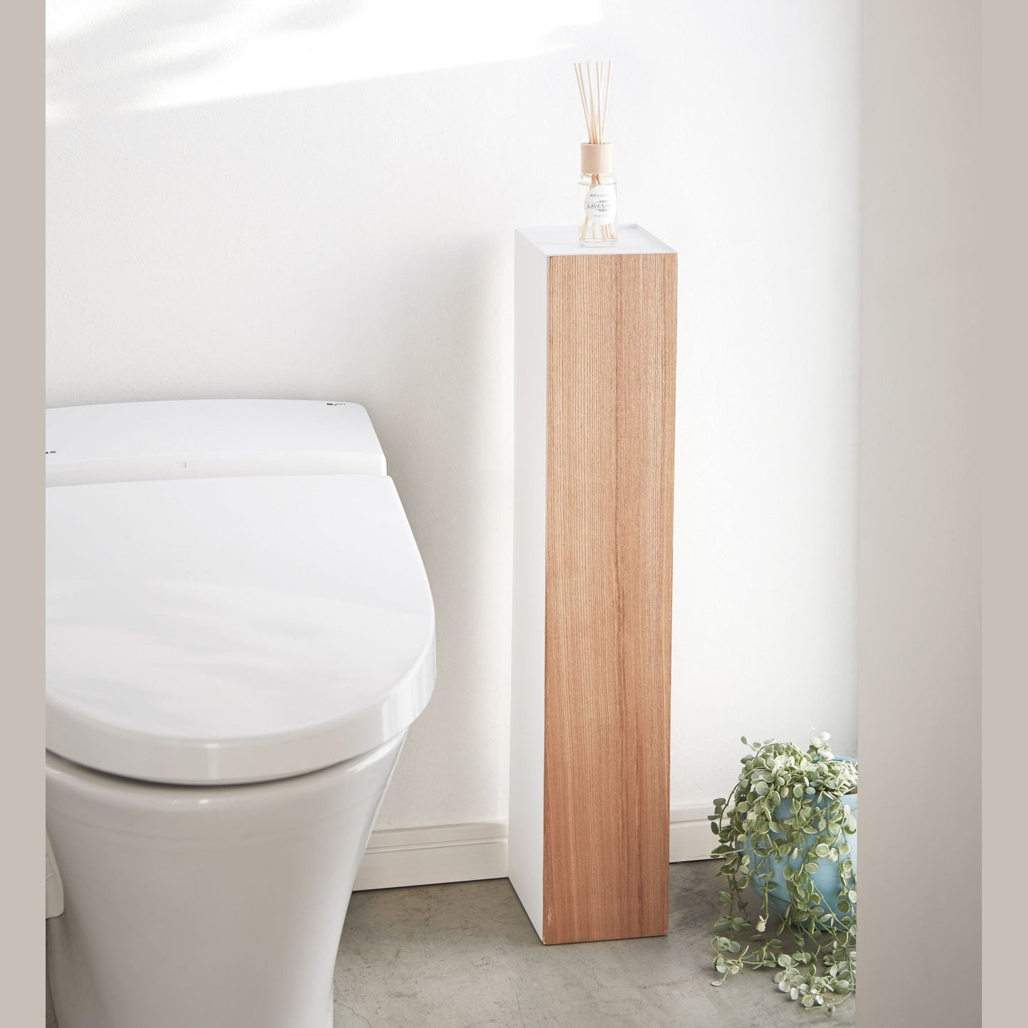 Front view of Toilet Paper Stocker displaying fragrance bottle in bathroom by Yamazaki Home.