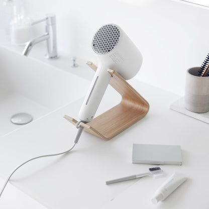 Hair dryer being stored on ash Yamazaki Home Hair Dryer and Iron Stand on a bathroom counter
