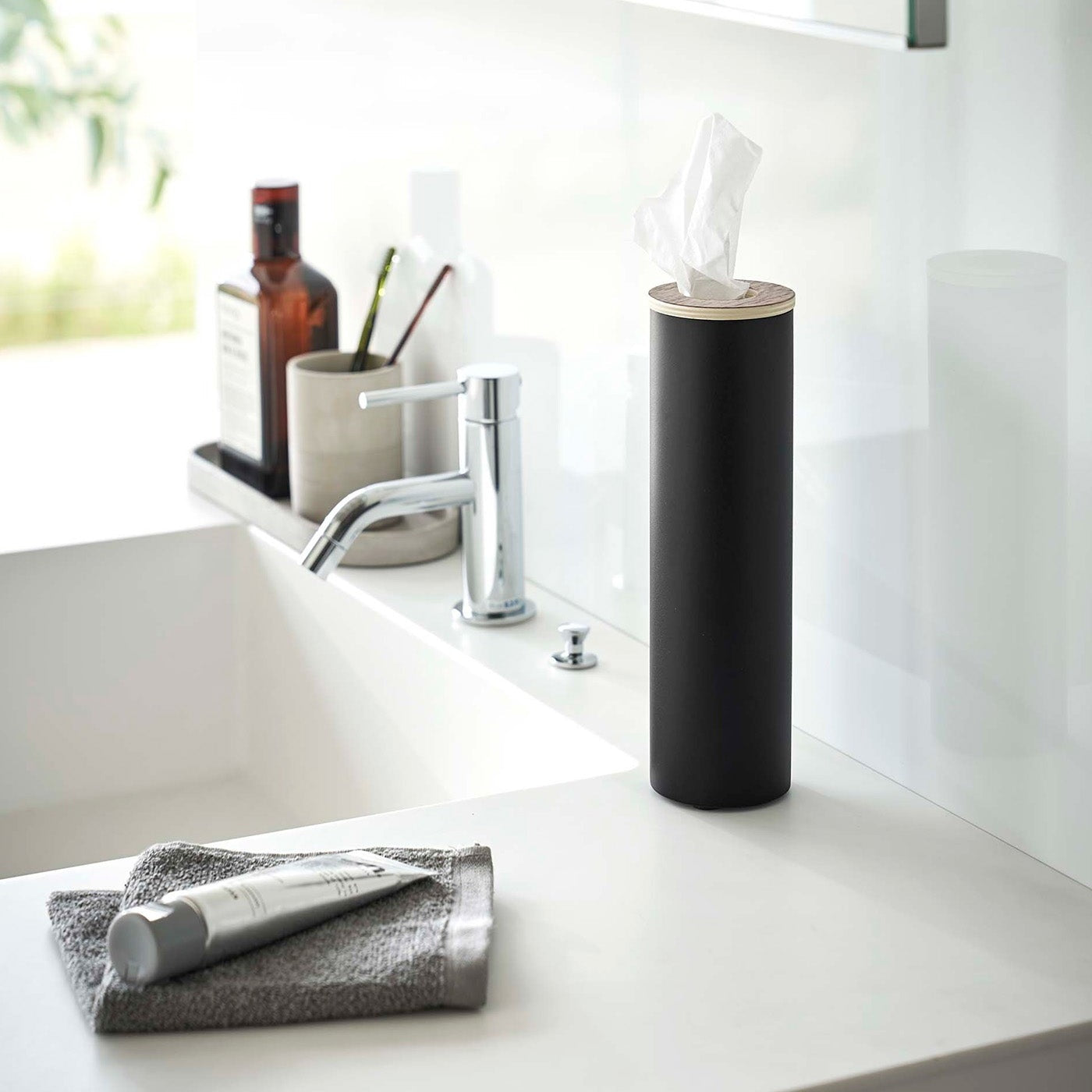 Small black Yamazaki Home Round Tissue Case on a sink counter