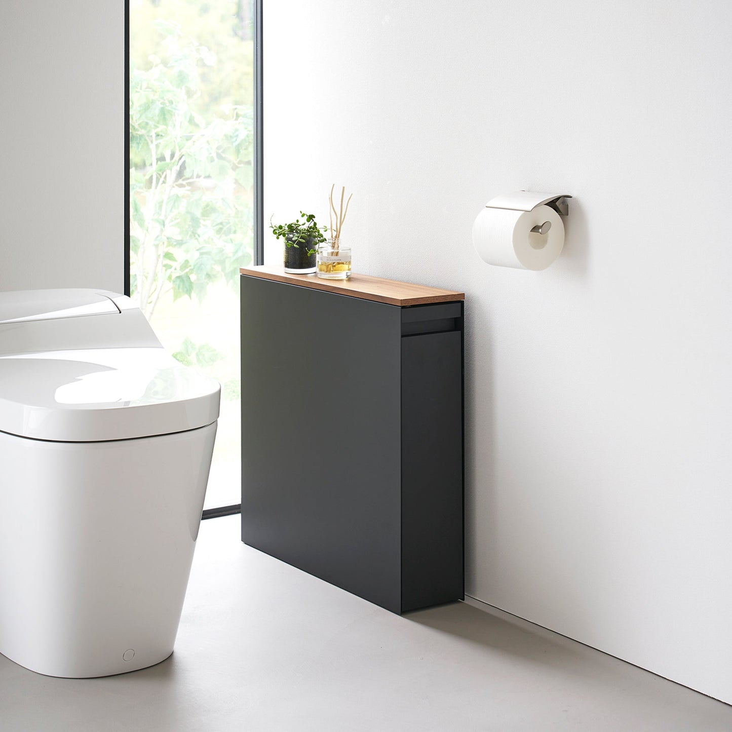 Black Yamazaki Home Pull-Out Bathroom Storage Cabinet next to a toilet in a bathroom