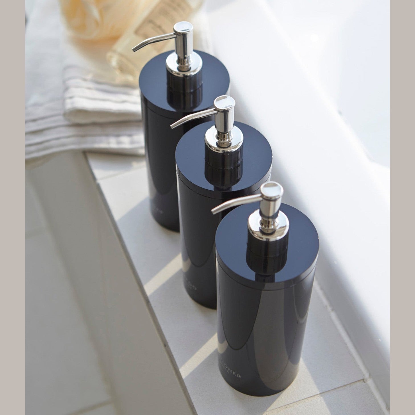 Aerial view of Yamazaki Home black Shampoo, Conditioner, and Body Soap dispensers in bathroom.