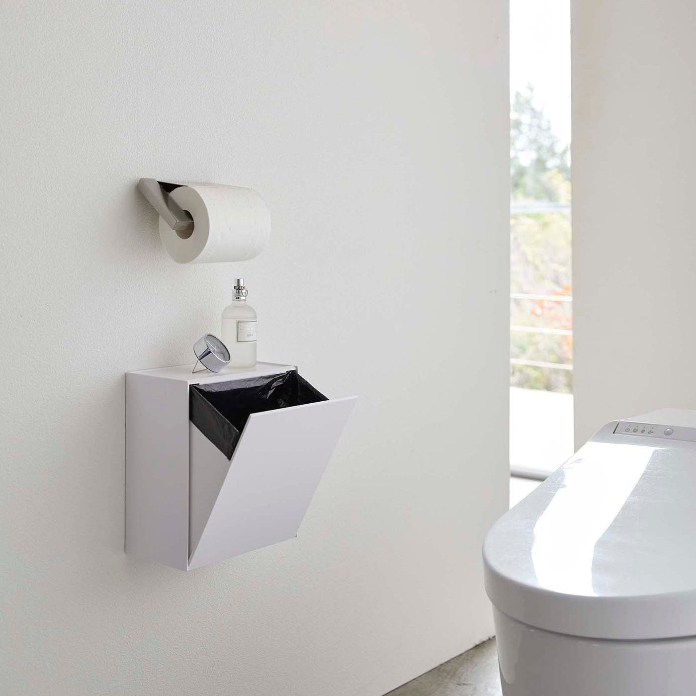 White Wall-Mount Storage open and holding trash bag on bathroom wall by Yamazaki Home.