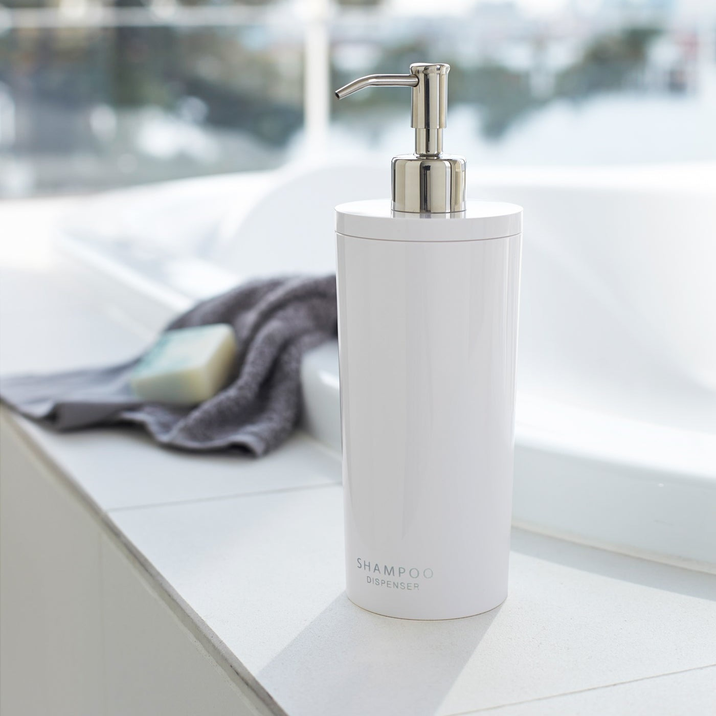 Front view of white Shampoo Dispenser on bathtub edge by Yamazaki Home.