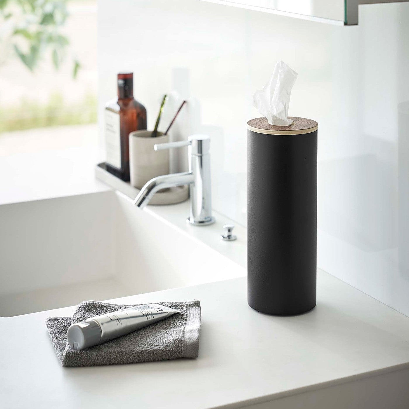 Large black Yamazaki Home Round Tissue Case on a sink counter
