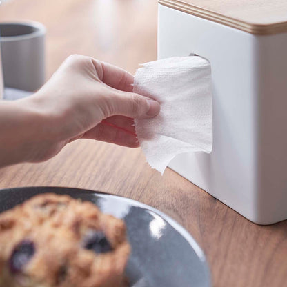 Person removing paper from white toilet paper holder on tabletop by Yamazaki Home.