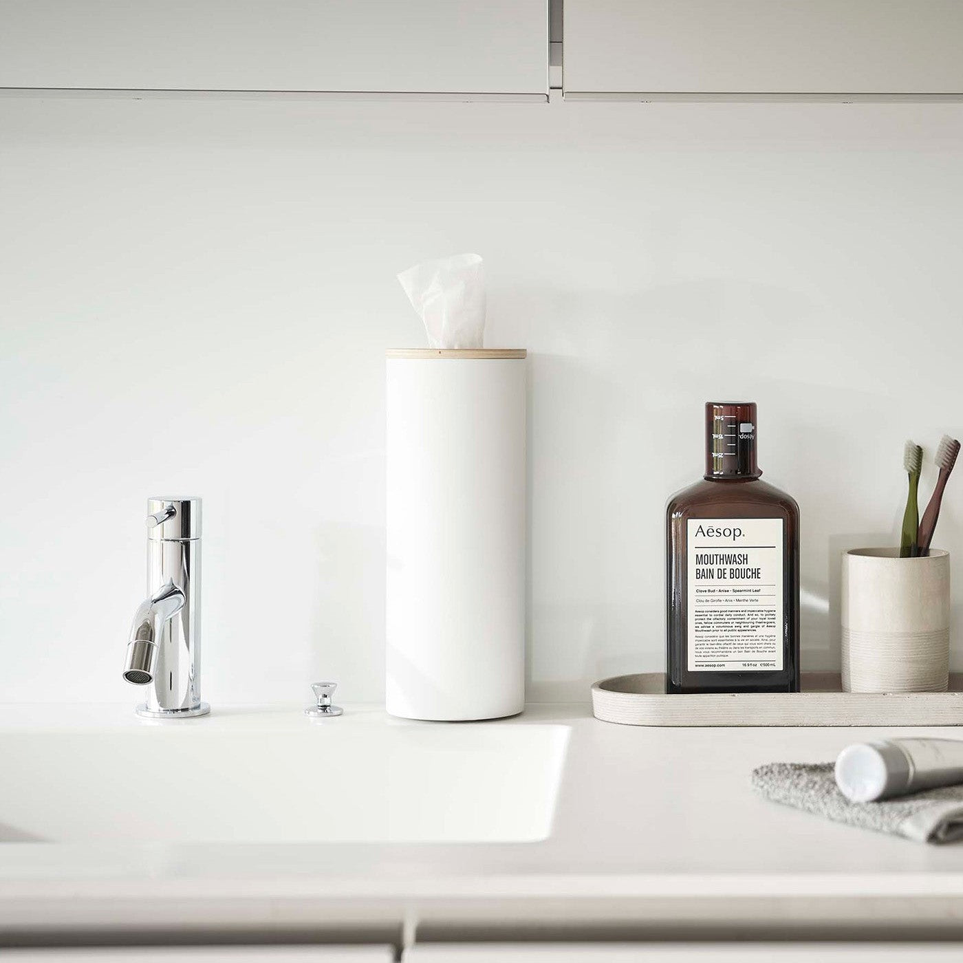 Large White Yamazaki Home Round Tissue Case on a bathroom sink counter