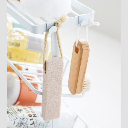 Close up corner view of white Freestanding Shower Caddy hooks holding sponge and brush by Yamazaki Home.