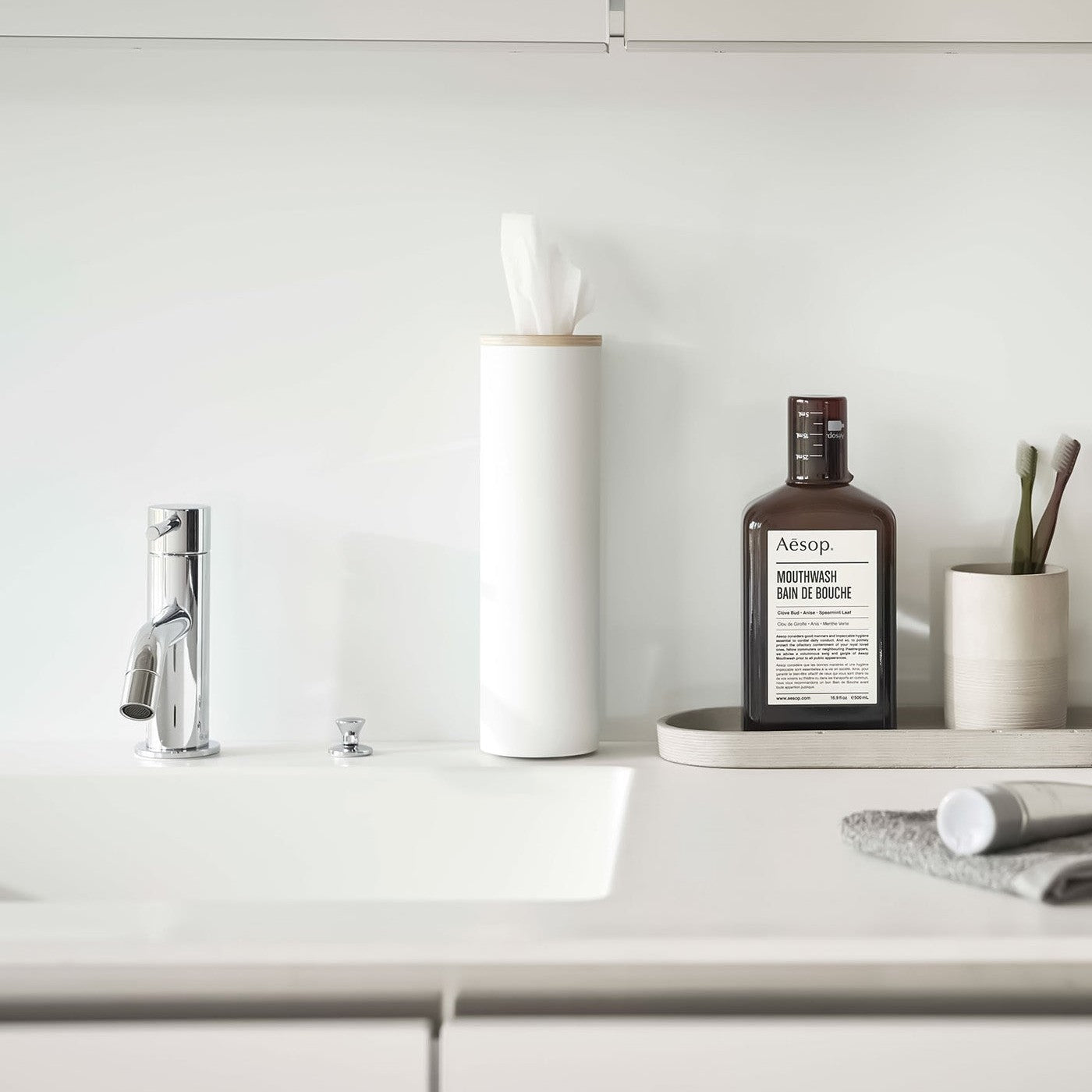 Small white Yamazaki Home Round Tissue Case on a bathroom sink counter