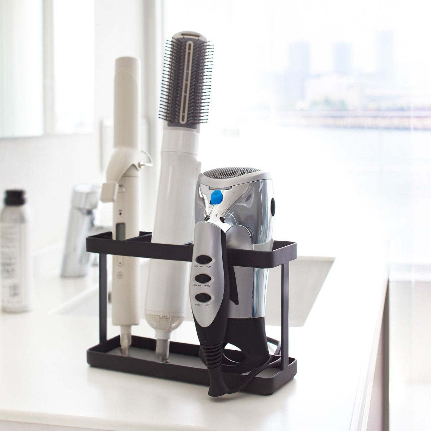 Black Haircare Appliance Holder displaying hair tools in bathroom by Yamazaki Home.