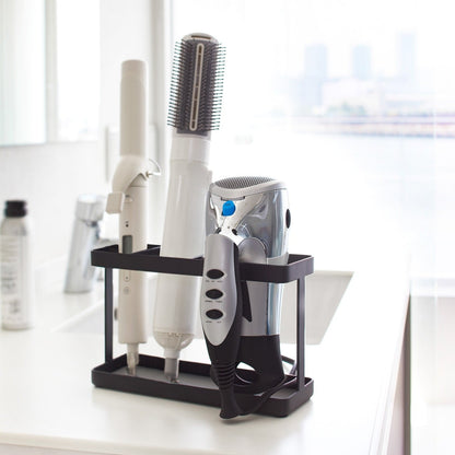Black Haircare Appliance Holder displaying hair tools in bathroom by Yamazaki Home.