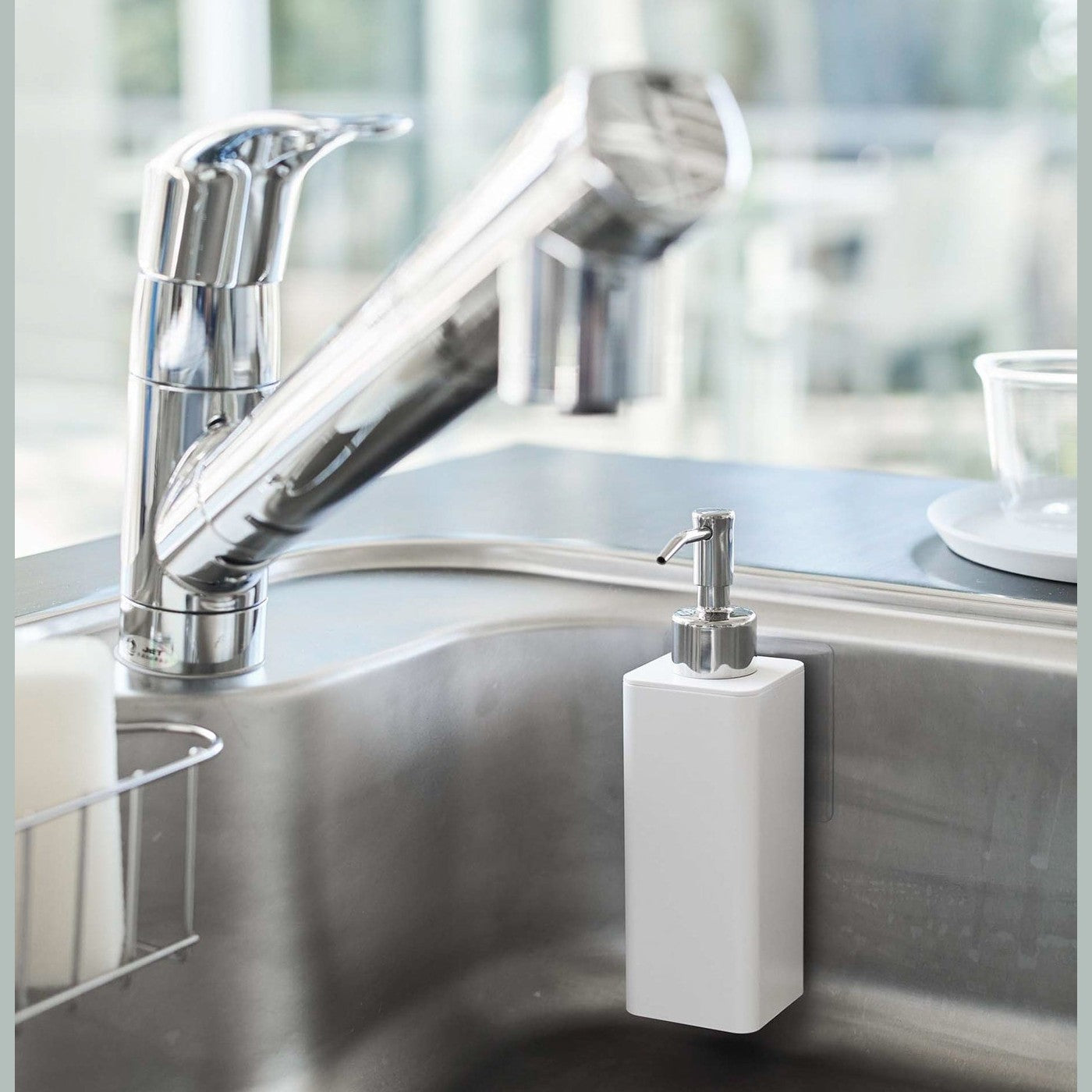 White Yamazaki Home square soap dispenser hooked on the side of kitchen sink