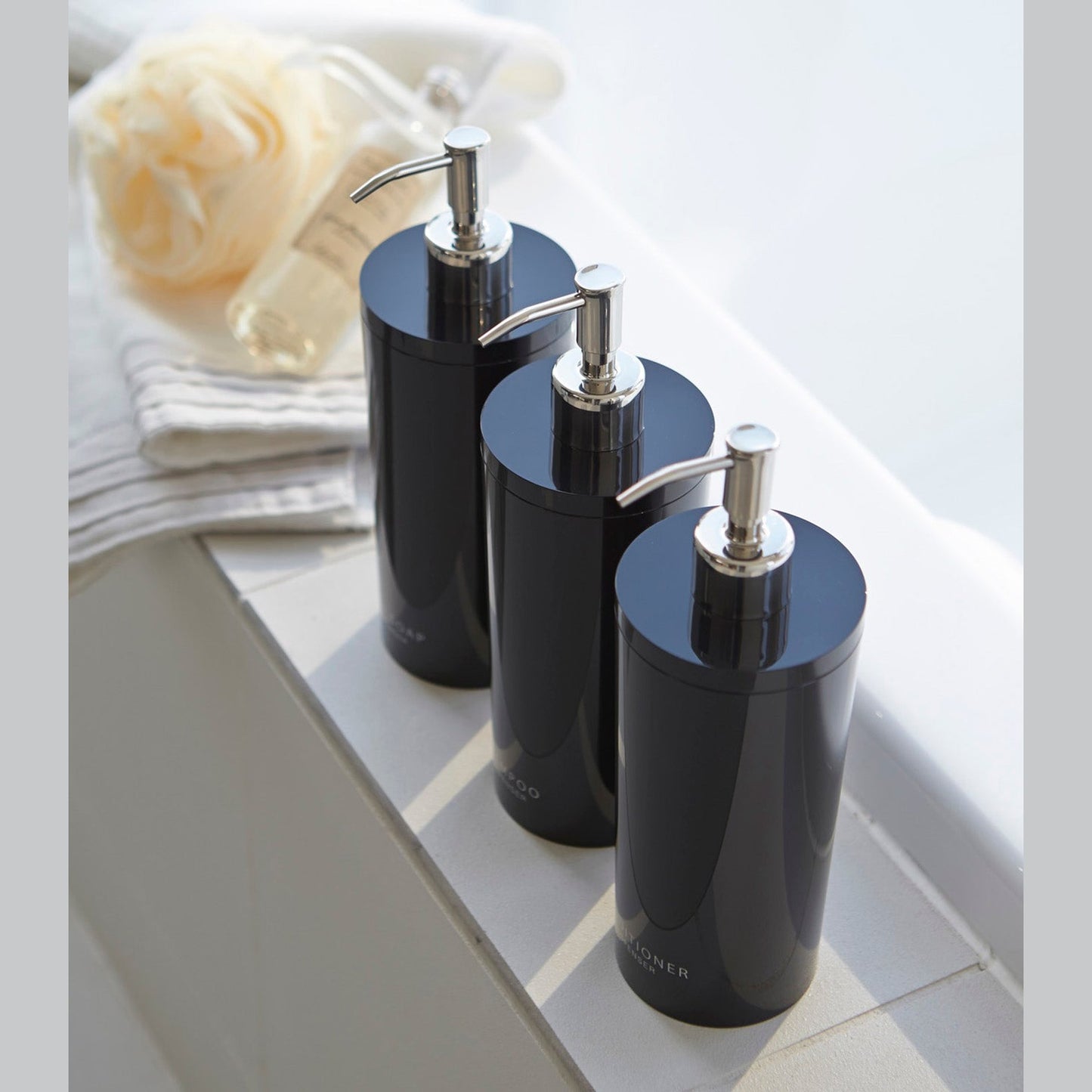 Aerial view of Yamazaki Home black Shampoo, Conditioner, and Body Soap dispensers in bathroom.