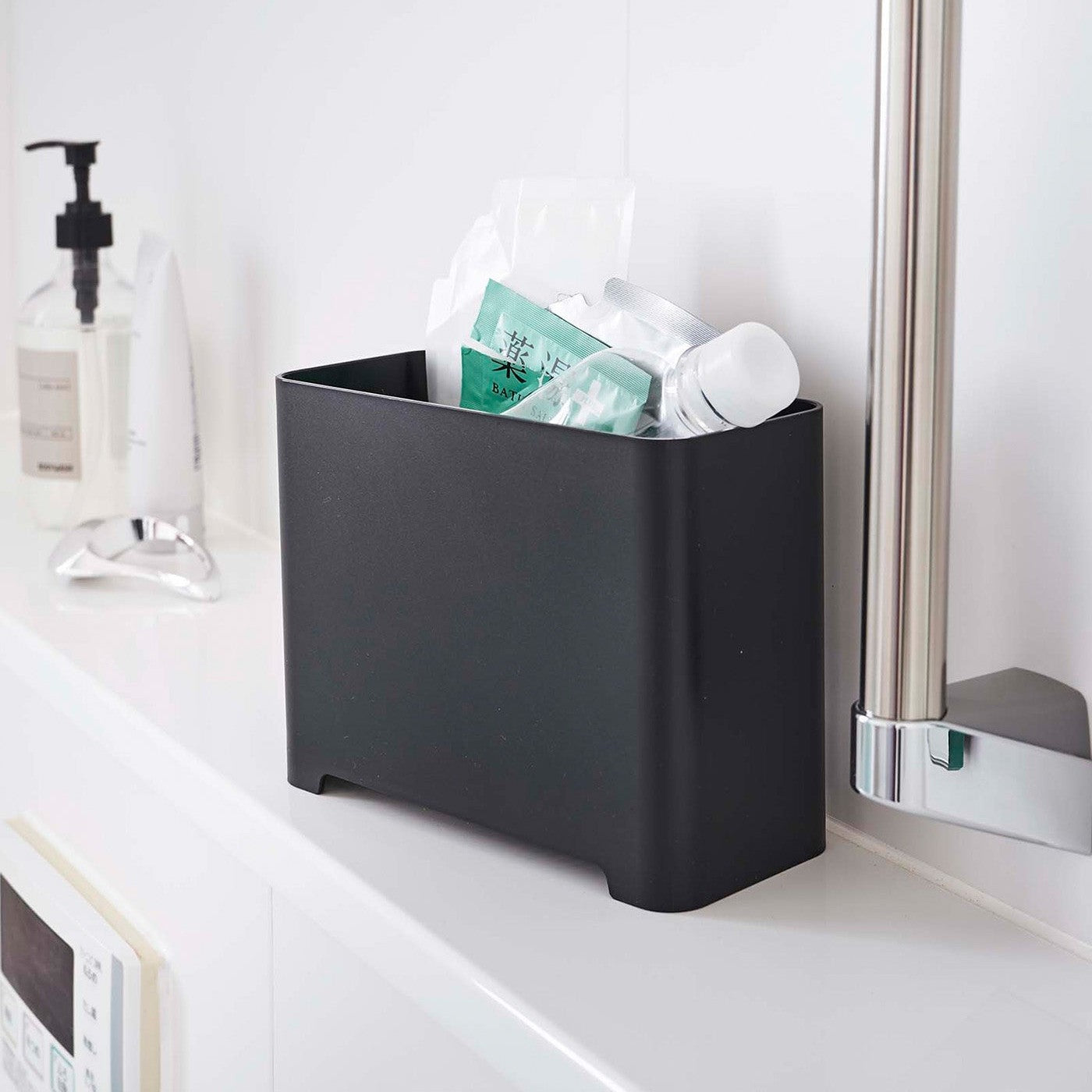 Black Yamazaki Self-Draining Bathroom Organizer filled with bath supplies