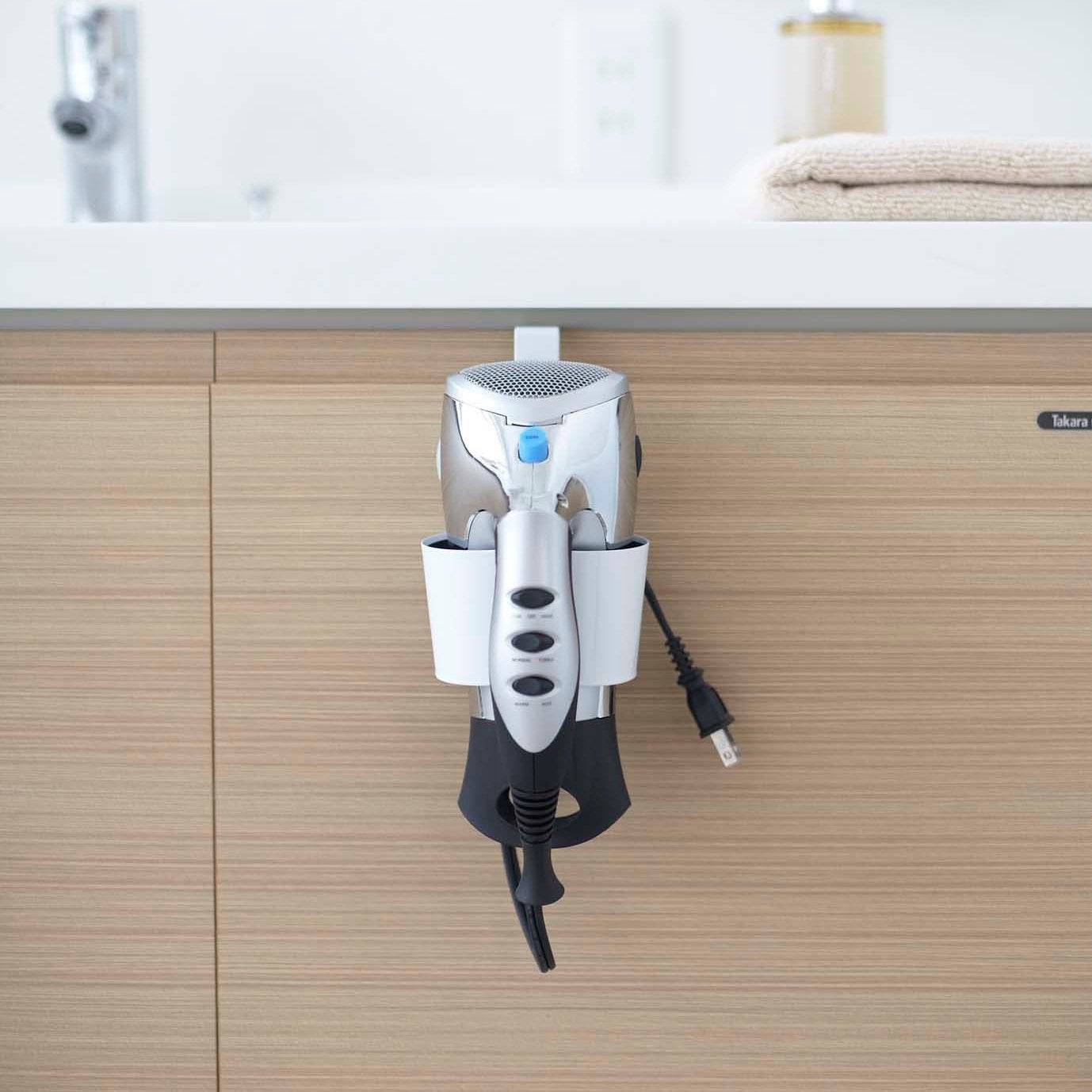 Front view of Blow Dryer Holder holding blow dryer in bathroom by Yamazaki Home.