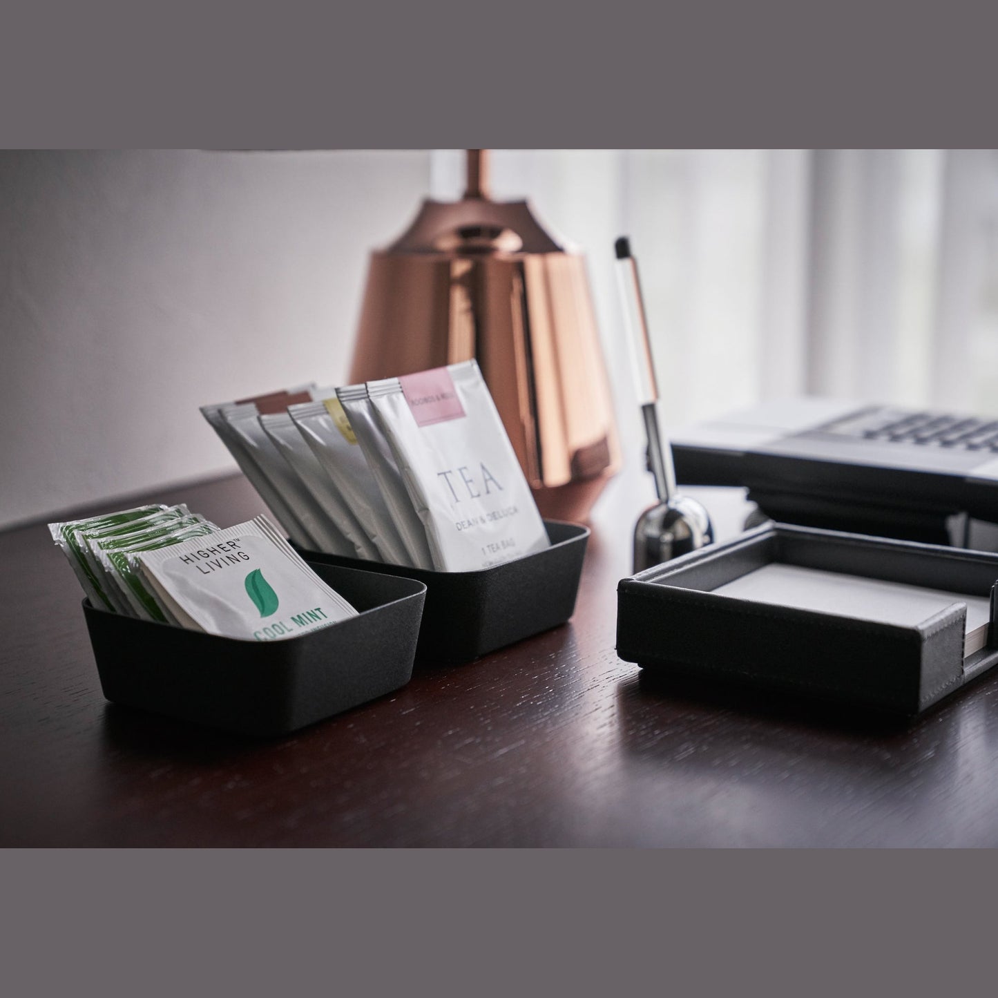Side view of black Accessory Trays holding tea bags on desk by Yamazaki Home.