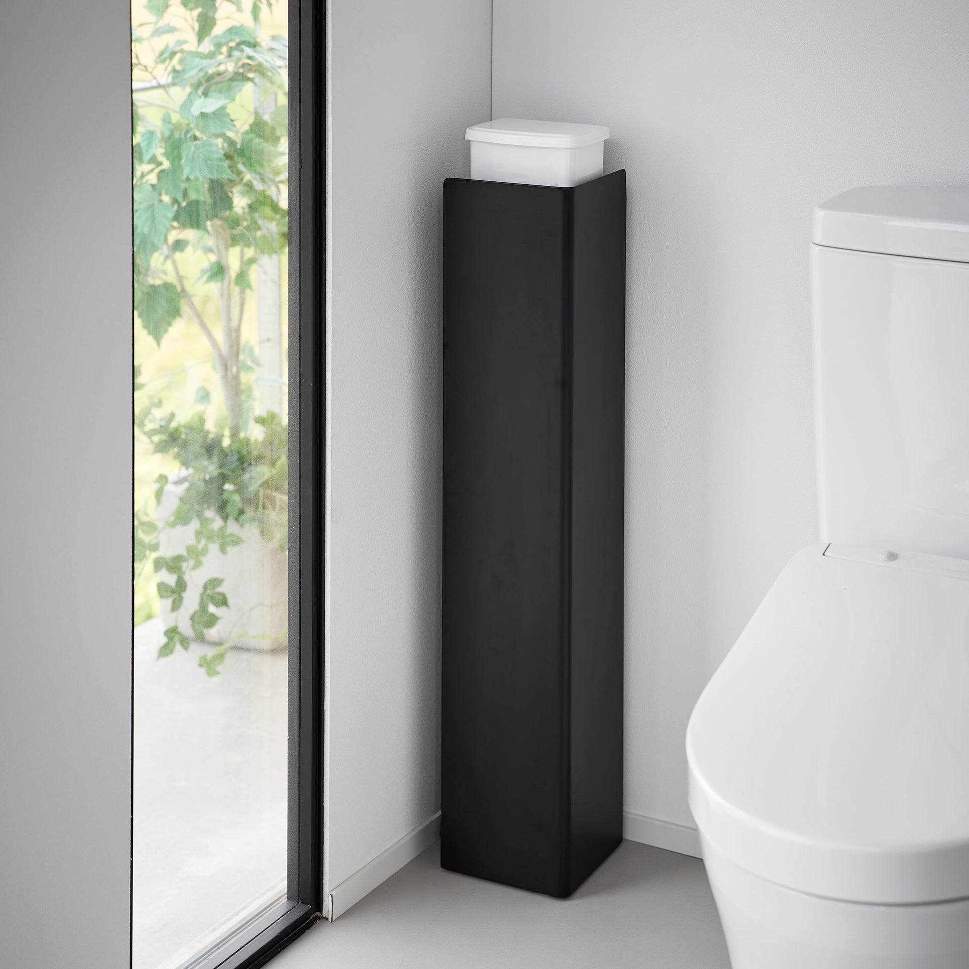 Black Yamazaki Home Rolling Bathroom Organizer turned around to conceal the toilet brush and other items stored