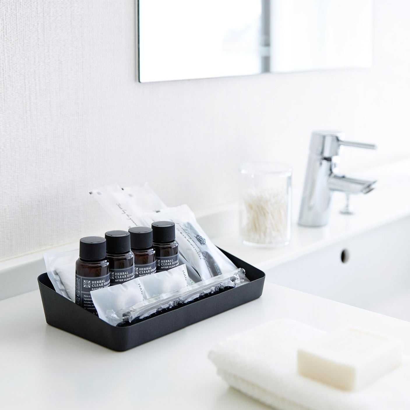 Black Accessory Tray holding beauty products in bathroom by Yamazaki Home.